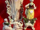 deux figurines assises l'une à côté de l'autre sur un tissu rouge