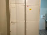 a tall white cabinet in the corner of a room
