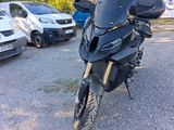 a black motorcycle parked in a parking lot next to a white car