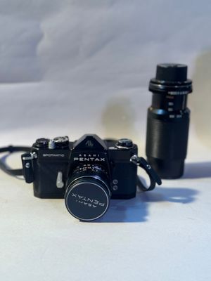 a black camera and a black bottle on a white table