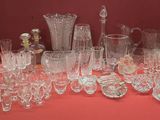 de nombreux verres et vases posés sur une table avec un fond rouge