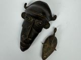 une image représentant un masque en bronze et un poisson sur un fond blanc