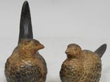 une paire d'oiseaux en céramique posés l'un sur l'autre sur une surface blanche