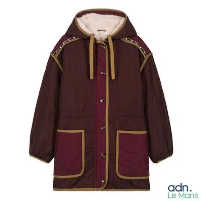La veste est bordeaux et marron et est dotée d'une capuche.