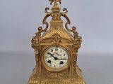 a gold clock sitting on a table with a white background