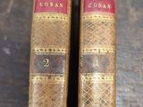 two old books sitting on top of a wooden table next to each other