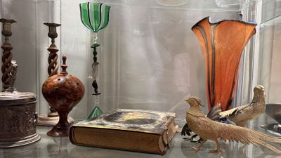 a glass display case with a book, vase, and bird figurines