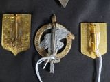 three badges and a pair of scissors on a black surface