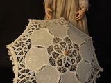 a doll that is holding a white umbrella on a black background