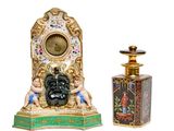 a small clock and a bottle of perfume on a white background