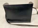 black leather shoulder bag with a strap on a white surface