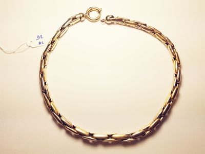 a close up of a gold chain bracelet on a white surface