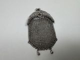 un petit sac à main en métal, muni d'une chaîne, posé sur une surface blanche