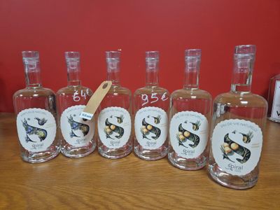 six bouteilles de gin posées sur une table en bois, avec une étiquette dessus