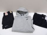 Un sweat à capuche, un pantalon de survêtement et d'autres pantalons de survêtement sont posés sur une table