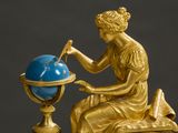 a gold statue of a woman sitting on top of a clock