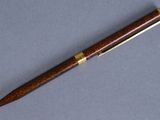 a wooden pen with gold trimming on a blue surface
