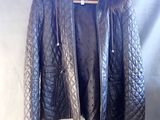 black leather jacket with fur collar and cuffs hanging on a hanger