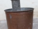 a brown pot with a black lid sitting on a cement floor