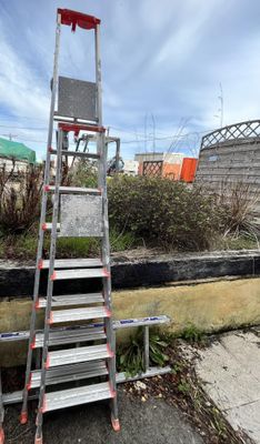 a ladder that is sitting on the ground next to a building