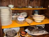 many plates and bowls on a shelf in the kitchen