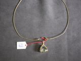 a close up of a gold necklace with a green stone on a red string