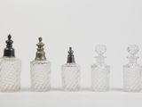 four glass bottles with silver tops and a silver stopper
