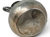 a silver cup with a handle on a white surface