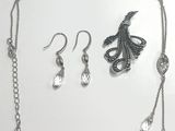 un collier, des boucles d'oreilles et une bague posés sur un fond blanc