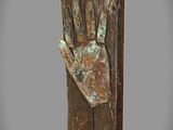 sculpture en bronze représentant une main tenant un morceau de bois, posée sur un socle