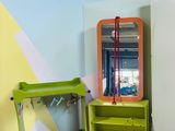 une étagère verte sur laquelle est posé un miroir, à côté d'une chaise verte