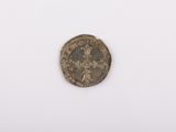 une vieille pièce de monnaie posée sur une surface blanche, avec un petit trou au milieu