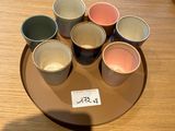 cinq tasses de couleurs différentes posées sur une assiette, sur une table