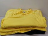 trois t-shirts jaunes empilés les uns sur les autres sur une table