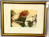framed picture of a painting of a river with buildings in the background