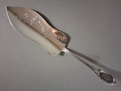 une cuillère en argent avec un manche en argent posée sur une table