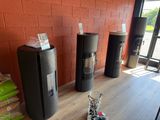 trois poubelles noires posées par terre à côté d'un mur de briques rouges