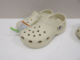 a pair of crocs on a table next to a pair of shoes