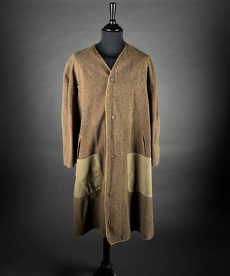 a brown coat on a mannequin stand against a black background