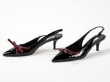 a pair of black shoes with red bows on the toes