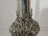 a silver vase with flowers in it sitting on a table