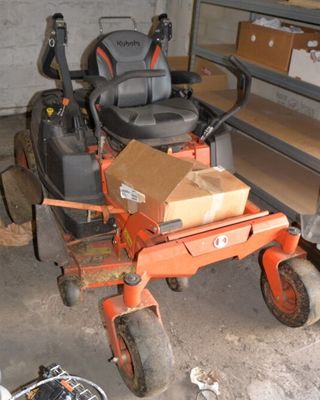 a lawn mower sitting in a garage with a box on the back of it
