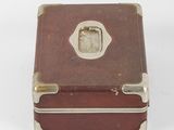 a small brown box with a silver handle on a white surface