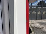 a white refrigerator sitting outside of a building with a red door