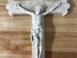 une statue de Jésus sur une croix posée sur un plancher en bois