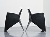 pair of black chairs in a white room with a white wall