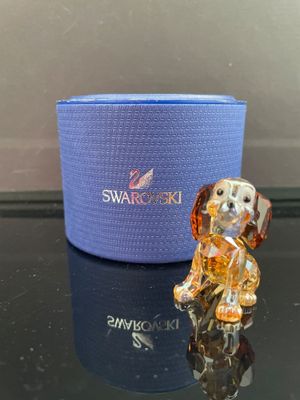 une figurine de chien en verre posée sur une table, à côté d'une boîte bleue