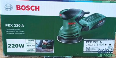 le boîtier d'une ponceuse orbitale Bosch PX220A posé sur une surface en bois