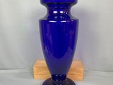 un vase bleu posé sur un socle en bois