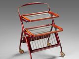 a red metal and glass trolley with a magazine rack on wheels